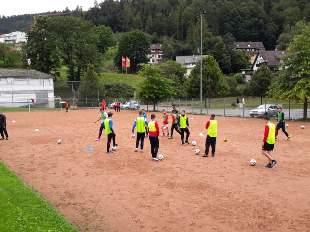 Außenplatz mit rotem Sand und Fußballspielern