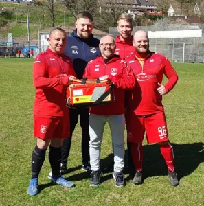 Gruppenfoto Spieler in roter Vereinskleidung Verbandskasten haltend