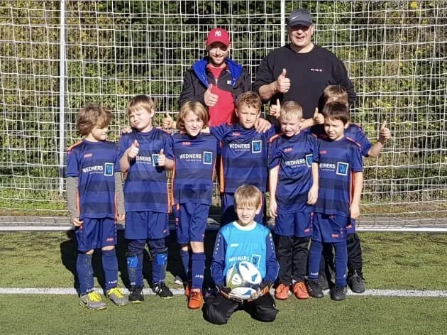 Mannschaftsfoto F-Jugend auf grünem Rasen vor Fußballtor mit Trainer