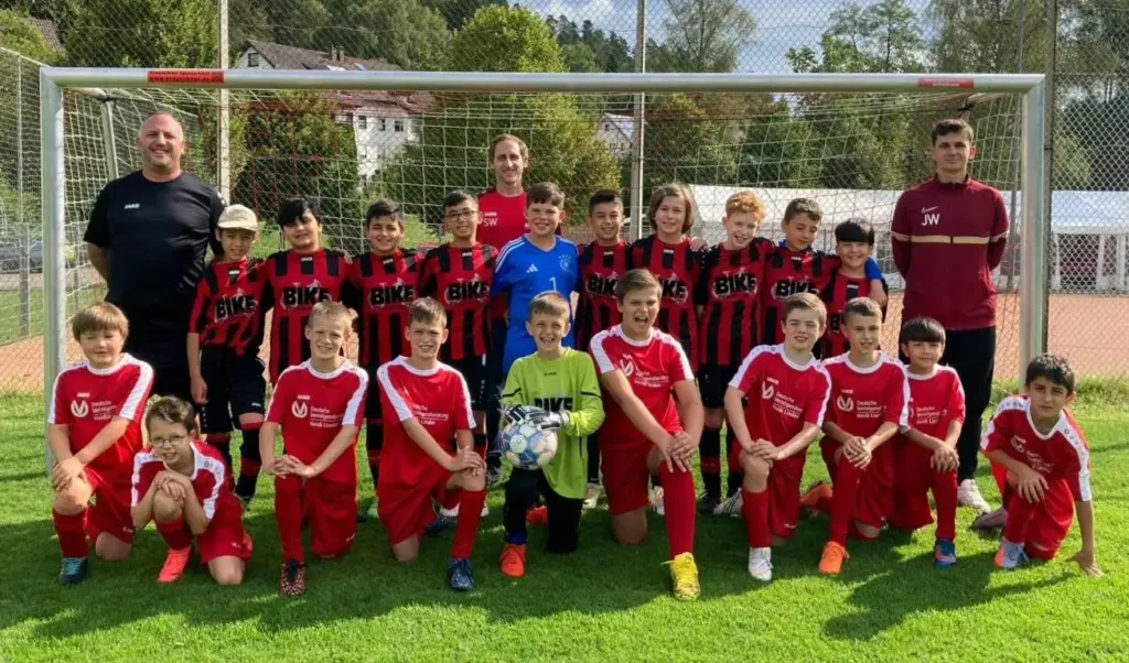 Mannschaftsfoto E-Jugend auf grünem Rasen vor Fußballtor mit Trainern